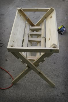 a table made out of wooden planks sitting on top of cement floor next to a tool box