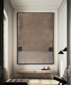 a large painting hanging on the wall above a bench in a room with white walls