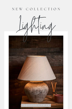 a lamp sitting on top of a wooden table next to a book with the title new collection lighting