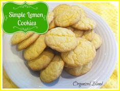 a white plate topped with cookies on top of a yellow table cloth next to a green sign that says simple lemon cookies