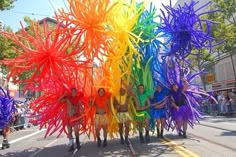 a group of people standing next to each other in front of a rainbow colored sculpture