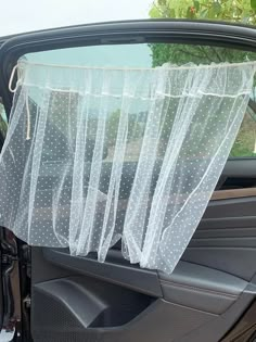 there is a car with a sheer curtain in the back seat and it's door open