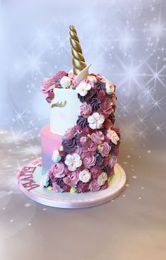 a pink and white cake with a unicorn horn on it's top that has flowers all over it