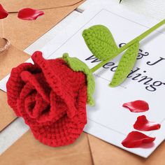 a crocheted rose sitting on top of a piece of paper next to a envelope