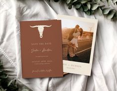 an image of a wedding card and save the date photo on a bed with greenery