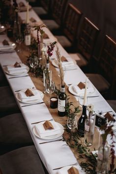 a long table is set with place settings and wine bottles, candles, and flowers