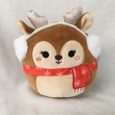 a brown and white stuffed animal with reindeer antlers on it's head wearing a red scarf