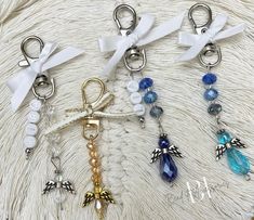 four key chains with charms on them sitting on a white surface, one has an angel charm and the other has a bow