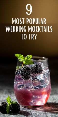 a glass filled with ice and blackberries on top of a table next to some mint leaves