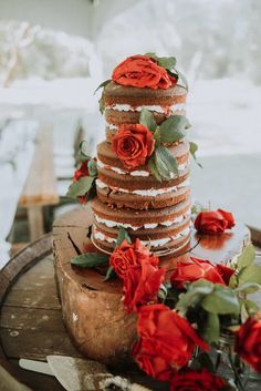 a wedding cake with red roses on top