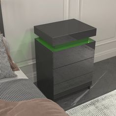 a black night stand next to a bed with pillows on it and a checkered pillow