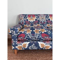 an upholstered blue floral chair with wooden legs and foot rests on a brown rug