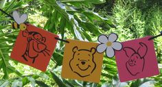 winnie the pooh bunting banner hanging on a string with flowers and other decorations