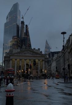 an empty city street in the rain with buildings on either side and people walking around