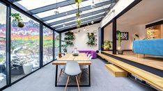 a dining room table with chairs and benches in front of a glass wall that overlooks a colorful landscape