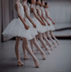 several ballerinas are lined up in white tutus