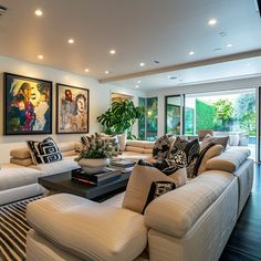 a living room filled with lots of furniture and paintings on the wall above it's windows