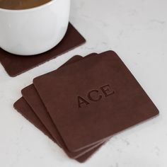 three coasters with the word ace on them and a cup of coffee in the background