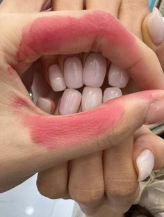 someone holding their hand out to show off some pink colored teeth