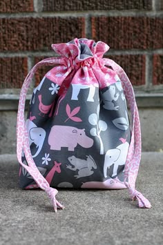 a bag sitting on the ground next to a brick wall with pink ribbon around it