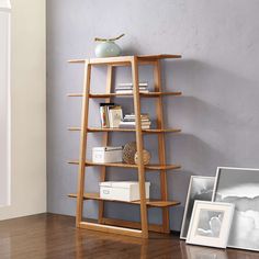 a wooden book shelf sitting on top of a hard wood floor next to an open window