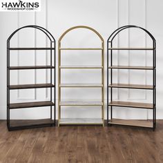 three bookshelves in the shape of archs against a white wall with wood flooring