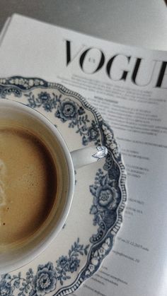 a cup of coffee sitting on top of a blue and white saucer next to a menu