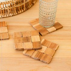 wooden coasters sitting on top of a table next to a glass and wicker basket