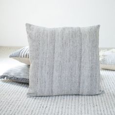 two pillows sitting on top of a bed next to each other in front of a white wall