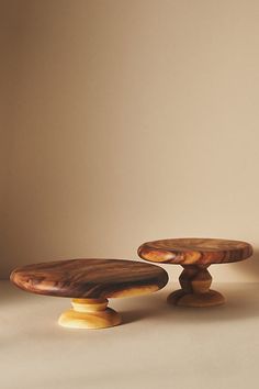 two small wooden cakes sitting on top of each other in front of a white wall