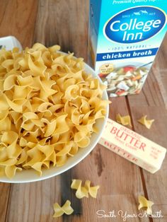 a white bowl filled with pasta next to a carton of butter