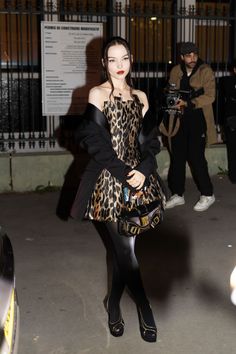 a woman in a leopard print dress and black tights is posing for the camera