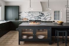 a large kitchen with marble counter tops and black cabinets, along with two stools