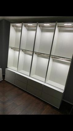 an empty walk - in closet with white shelves and lights on the wall above it