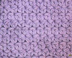 a close up view of a purple crocheted blanket with small circles on it