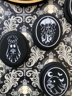 four black and white buttons with designs on them sitting next to a gold plated object