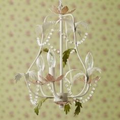 a white chandelier with flowers and leaves hanging from it's sides on a wall