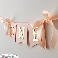 a pink banner with the word one hanging from it's side and ribbon on top