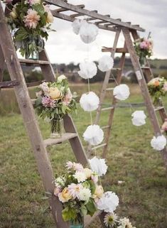 a ladder decorated with flowers and paper umbrellas for a wedding ceremony in the countryside