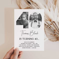 a person holding up a card with an image of two people in the center and text that reads, thomas black is turning 40