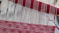 a close up of a weaving machine with red and white yarn