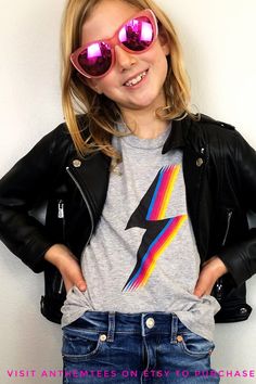 This Kids Lightning Bolt graphic tee is super cool and trendy! This kids shirt has an 80s and 90s vibe with it's bright rainbow colored graphic. This awesome kids shirt is a great kids gift. Our kids tshirts are made of the same highest quality soft, lightweight cotton as our adult shirts. This shirt features a modern unisex fit. Several color options to choose from. Check them and more out @AnthemTees on Etsy. Unisex Graphic Print Tops For School, Fun Multicolor Unisex Tops, Trendy Rainbow Graphic Print Tops, Preppy Lightning Bolt Shirt, Retro Multicolor T-shirt For School, Retro Character Print T-shirt For Spring, Tb Lightning Shirt, Lightning Bolt Clothes, Lightning Shirt