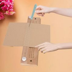 a person holding a blue toothbrush over a piece of cardboard with holes in it