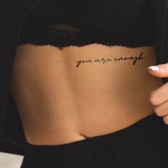 a woman's stomach with the words you are enough written on her back side