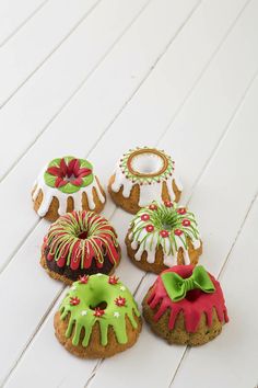 six decorated cookies sitting on top of a white wooden table next to each other with green and red icing