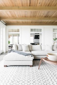 a living room with white furniture and wood ceiling