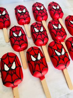 spiderman pops are sitting on top of a white table with red and black icing