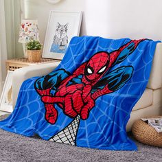 a spiderman blanket is on the floor next to a couch