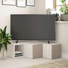 a flat screen tv sitting on top of a white shelf next to a potted plant