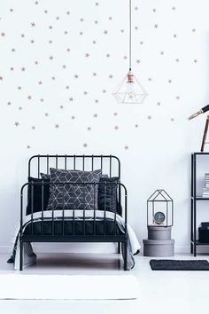 a white bedroom with stars on the wall and black bedding, along with a lamp